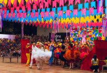 Dançarinos se apresentam em uma celebração cultural brasileira colorida, com enfeites ao redor.