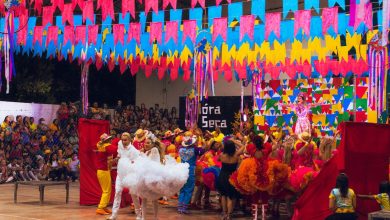 Dançarinos se apresentam em uma celebração cultural brasileira colorida, com enfeites ao redor.