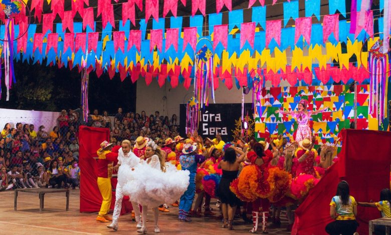 Dançarinos se apresentam em uma celebração cultural brasileira colorida, com enfeites ao redor.