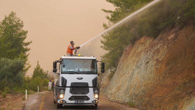 Bombeiros usam um canhão de água montado em um caminhão para combater um incêndio florestal.
