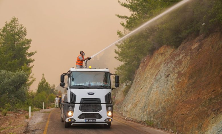 Bombeiros usam um canhão de água montado em um caminhão para combater um incêndio florestal.